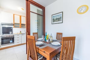 A modern kitchen with a dining area, including a table set for two with plates, glasses, and cutlery.