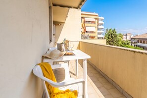 A balcony with a table, a chair, and a bottle of champagne.