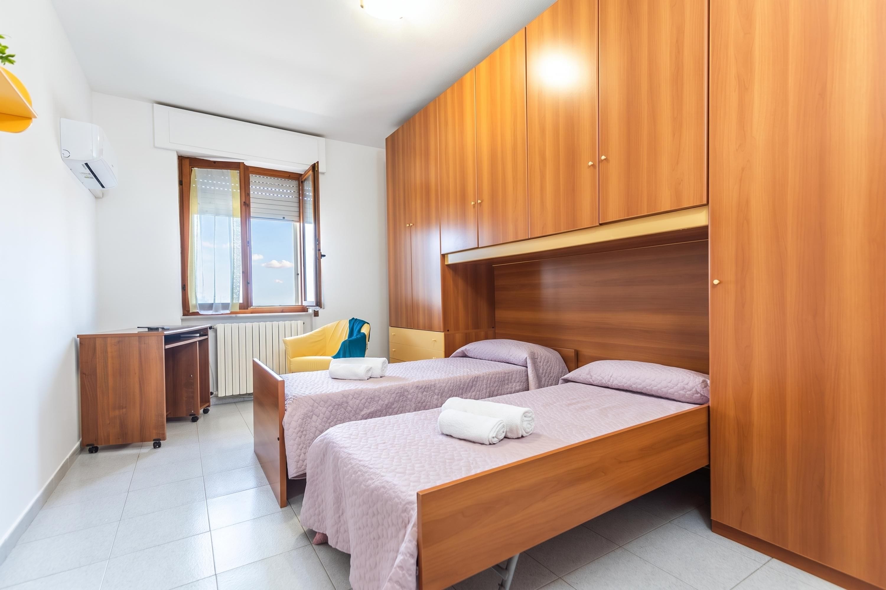 Ein kleines Schlafzimmer mit zwei Einzelbetten, einem Schreibtisch und einer Heizung.