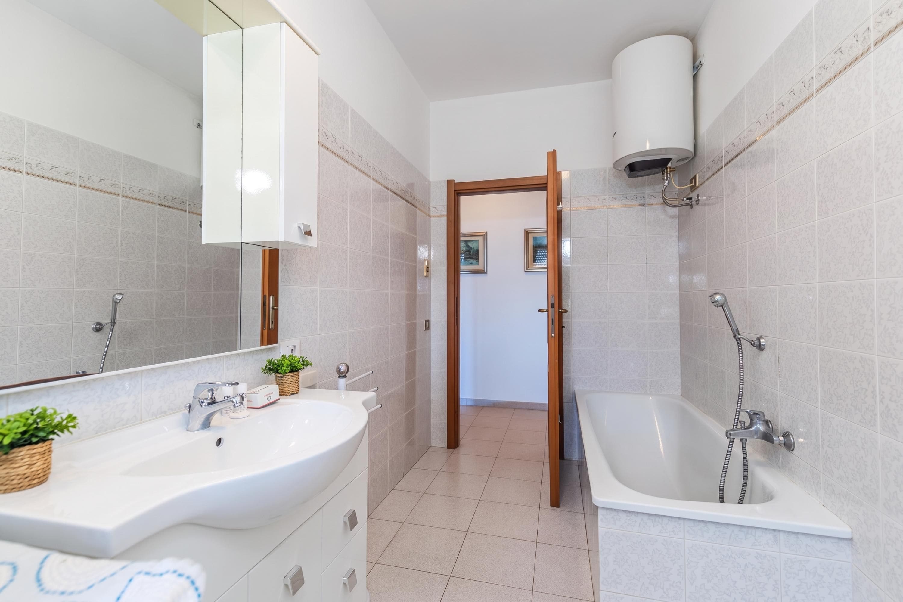 A modern bathroom with a large mirror, a sink, a bathtub, and a shower.