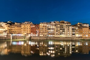 A nighttime cityscape with buildings reflected in calm water.