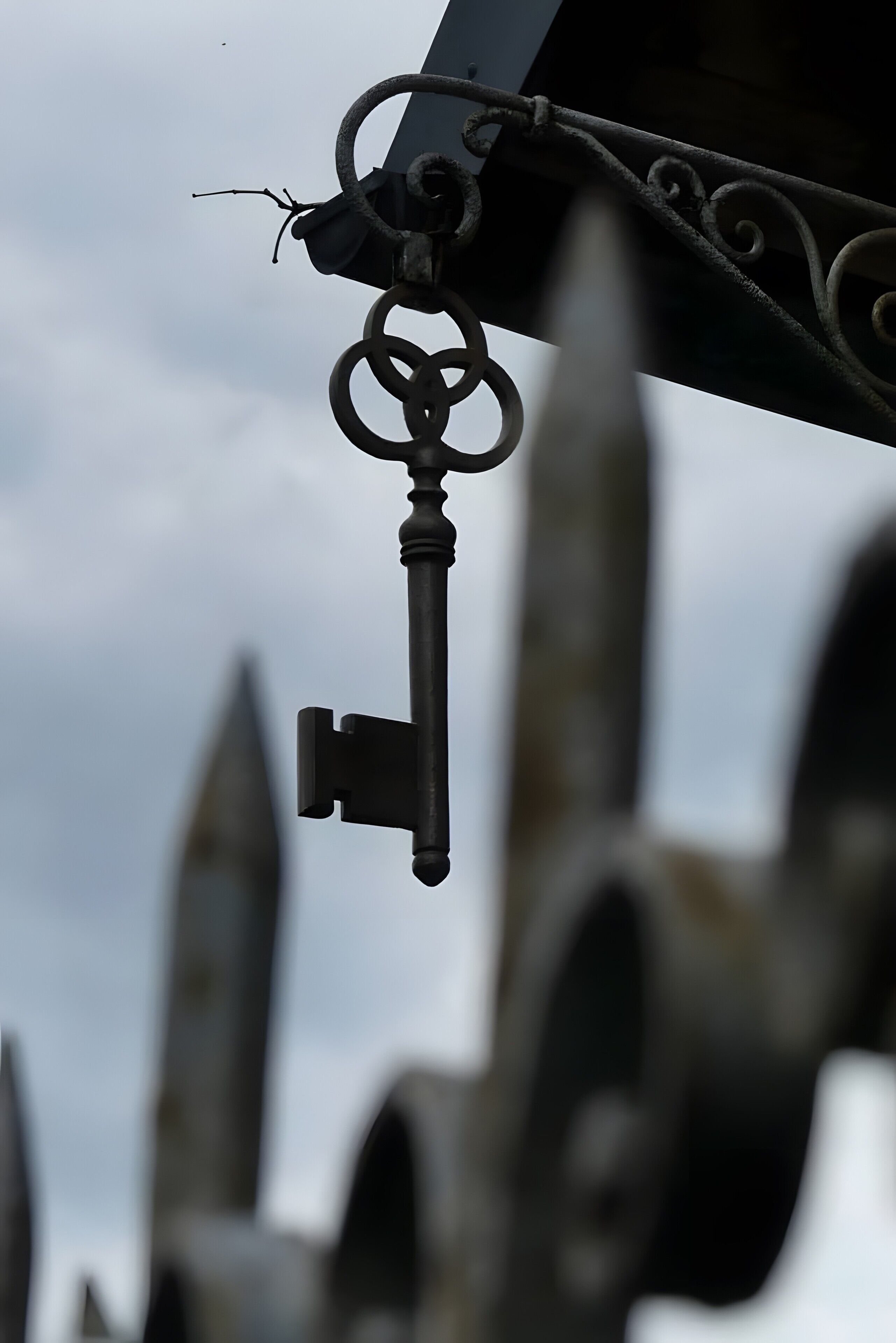 Een sleutel hangt aan een metalen constructie, met een vage achtergrond van architecturale details.