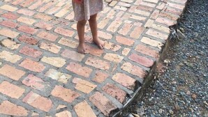 A child holding a sign that reads "Villa Trust" in front of a yellow building with brick steps and greenery in the background. - 5 Bedroom Waterfront Villa Tryst (Northside)