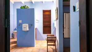 A bathroom with a blue wall, a wooden door, a white towel, a wooden bench, and a window with blinds. - 5 Bedroom Waterfront Villa Tryst (Northside)