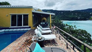 A poolside area with lounge chairs, a small pool, and a view of a body of water and hills. - 5 Bedroom Waterfront Villa Tryst (Northside)