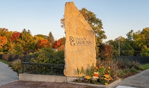 A large stone sign with 'Reiman Gardens Iowa State University' inscribed on it, surrounded by a landscaped area with various plants and flowers.