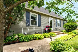 A residential house with a front yard, a small tree, and a potted plant.