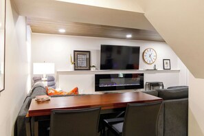 A modern living room with a flat-screen TV, a clock, and a fireplace.