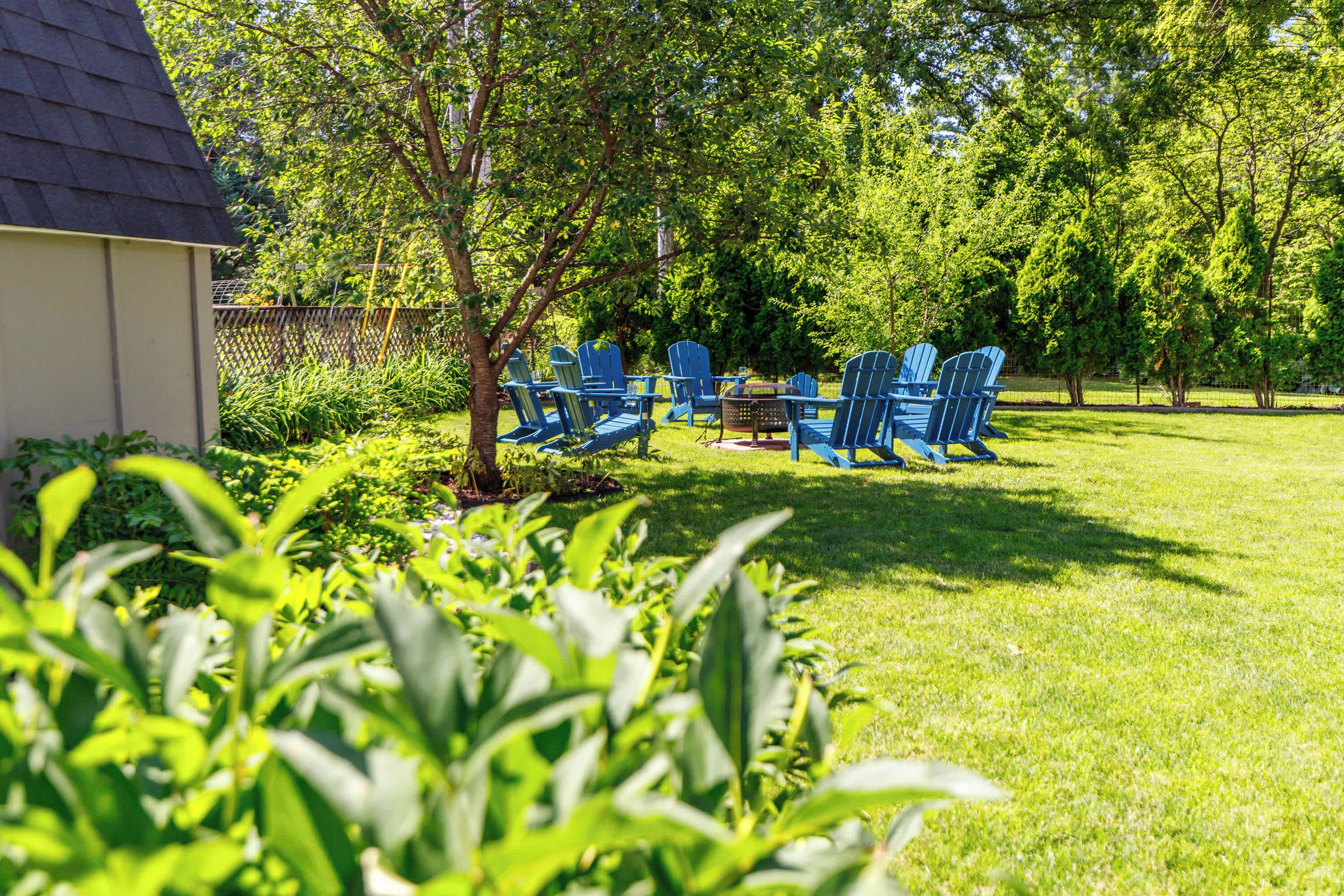 Un jardin avec une pelouse, une terrasse en bois et un petit abri de jardin.
