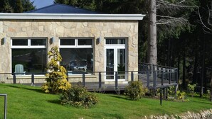 A stone building with a flat roof, large windows, and a covered porch. - Suite w/ Lake Views Near Excursions & Civic Center w/ Breakfast in Bariloche (San Carlos de Bariloche)