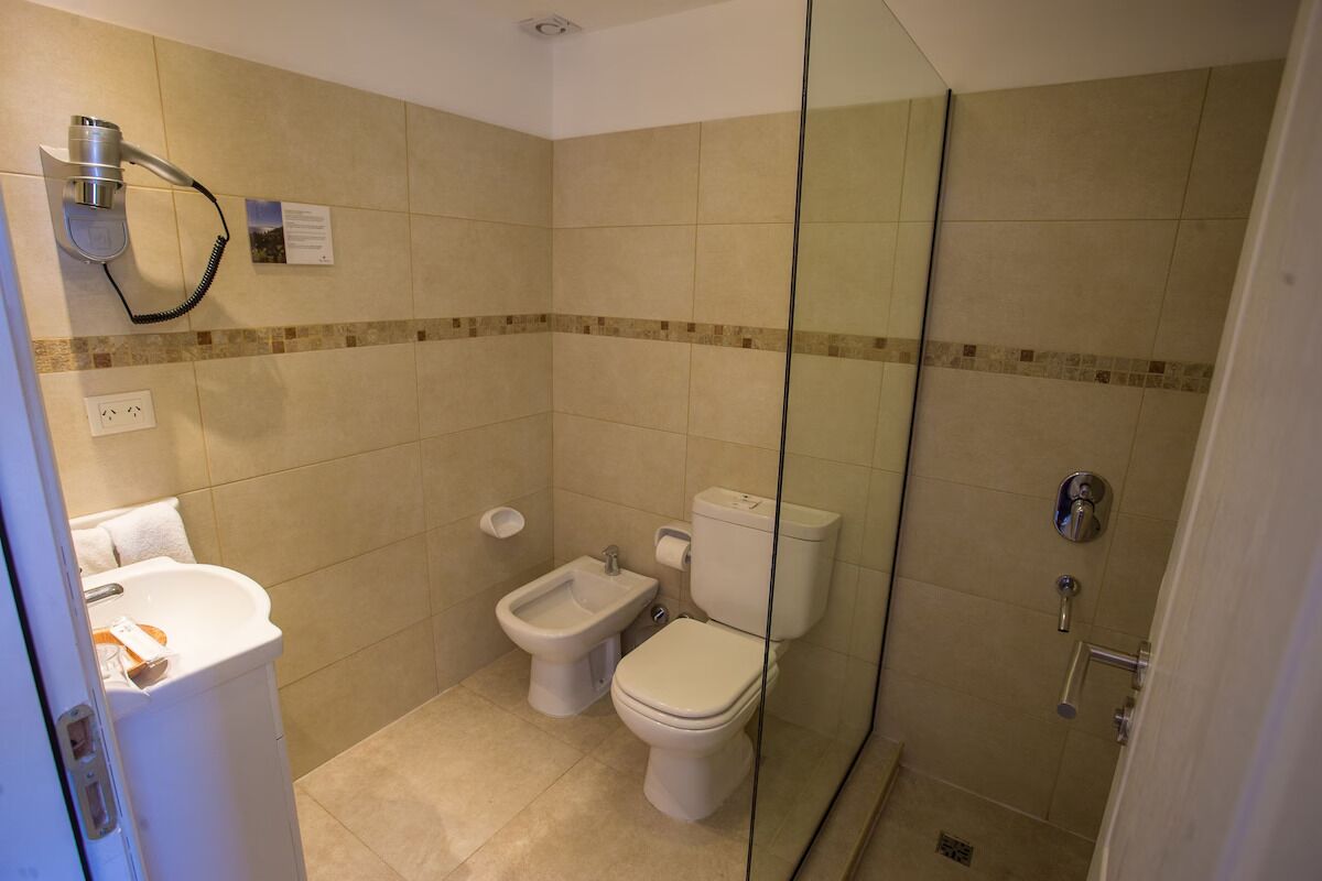 A bathroom with a toilet, bidet, and a glass-enclosed shower.