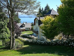 A residential area with houses, a tree-lined pathway, and a body of water in the background.
