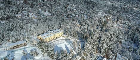 Una zona montañosa cubierta de nieve con varios edificios, incluyendo un hotel grande con varios pisos y otro edificio más pequeño cercano.