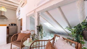 A cozy loft-style room with a dining area, kitchen, and a large skylight.
