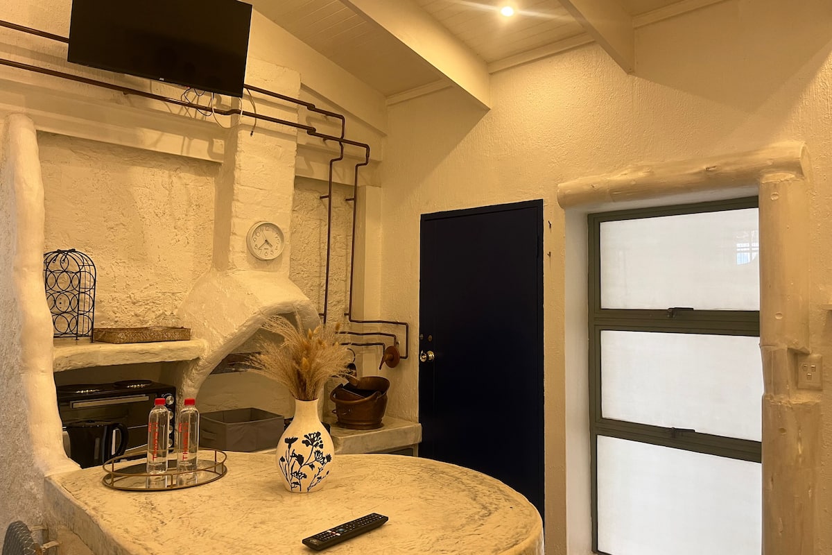 A kitchen with a marble countertop, a vase with dried plants, a clock, and a black door.