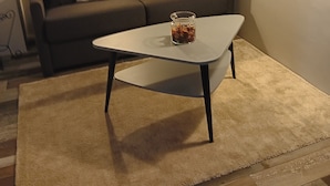 En stue med en sofa, et sofabord og et tæppe.