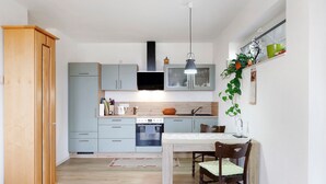 A compact kitchen with a dining area, wooden cabinets, a built-in oven, and a hanging plant.