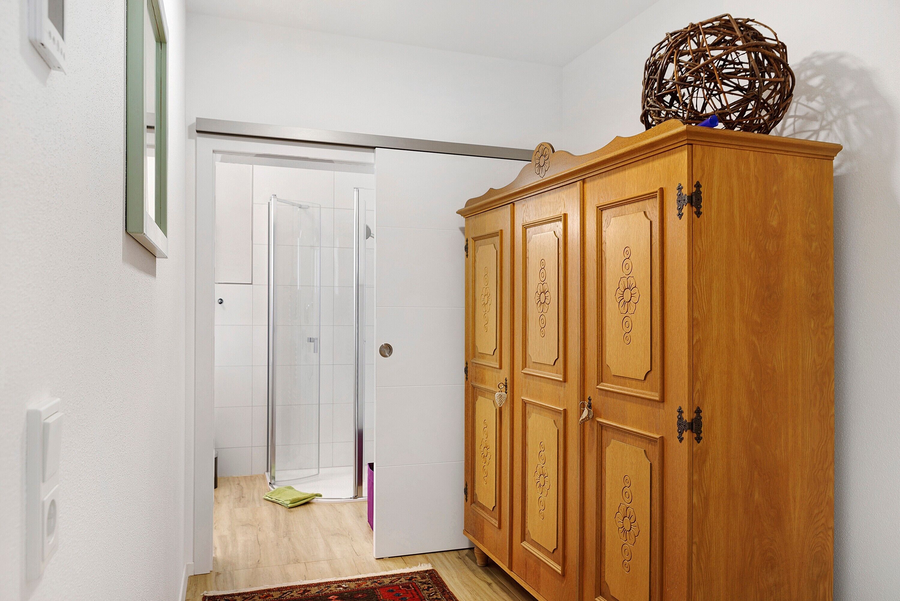 Ein Flur mit einem Holzschrank, einer Tür zu einem Badezimmer und einem gemusterten Teppich.
