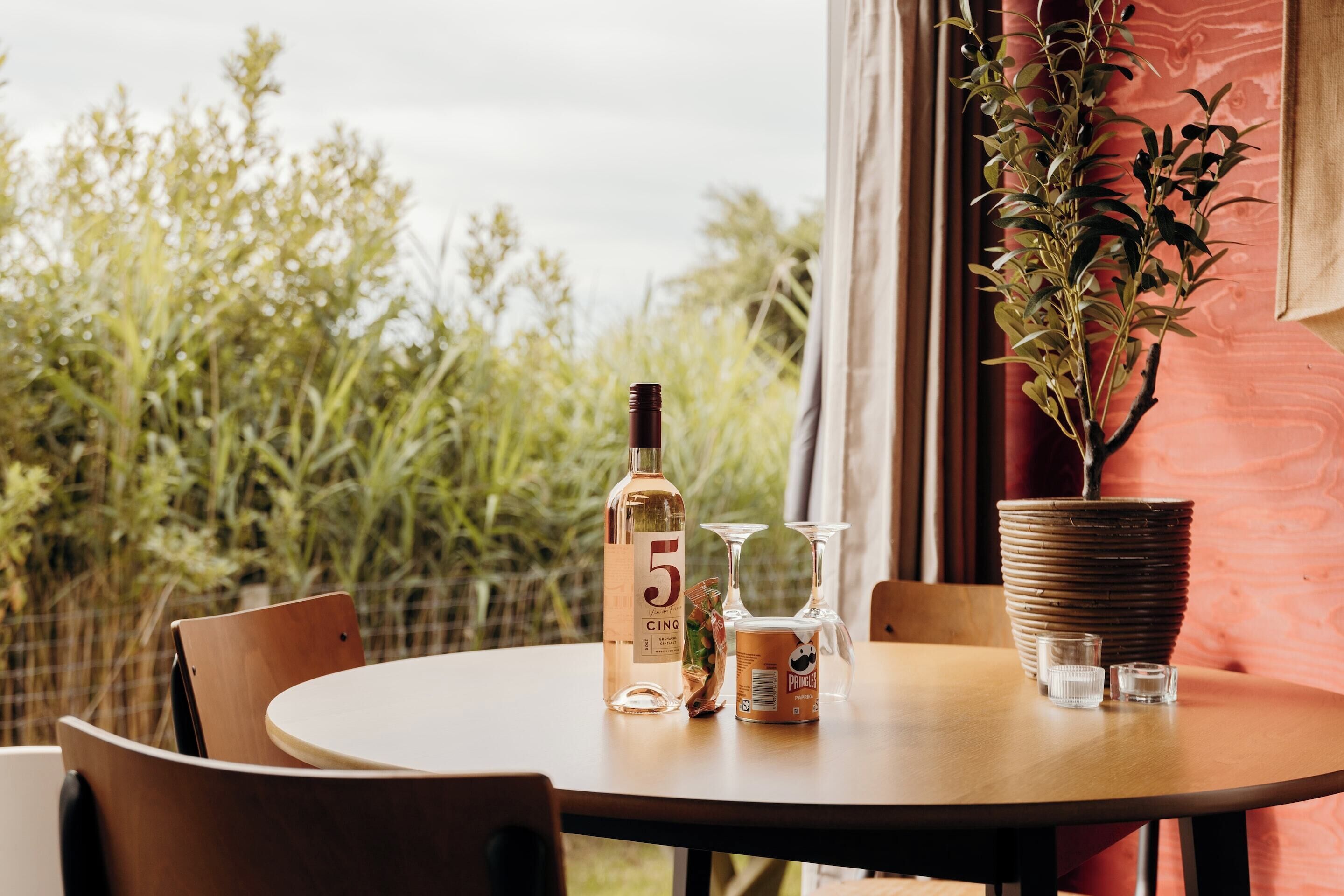 Un tavolo rotondo con una bottiglia di Cointreau, un bicchiere e una pianta in vaso.