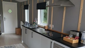 Ett modernt kök med en svart bänkskiva, vita skåp och en köksfläkt i rostfritt stål.