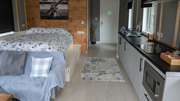Ett modernt sovrum med en stor säng, ett litet pentry och ett badrum med dusch.