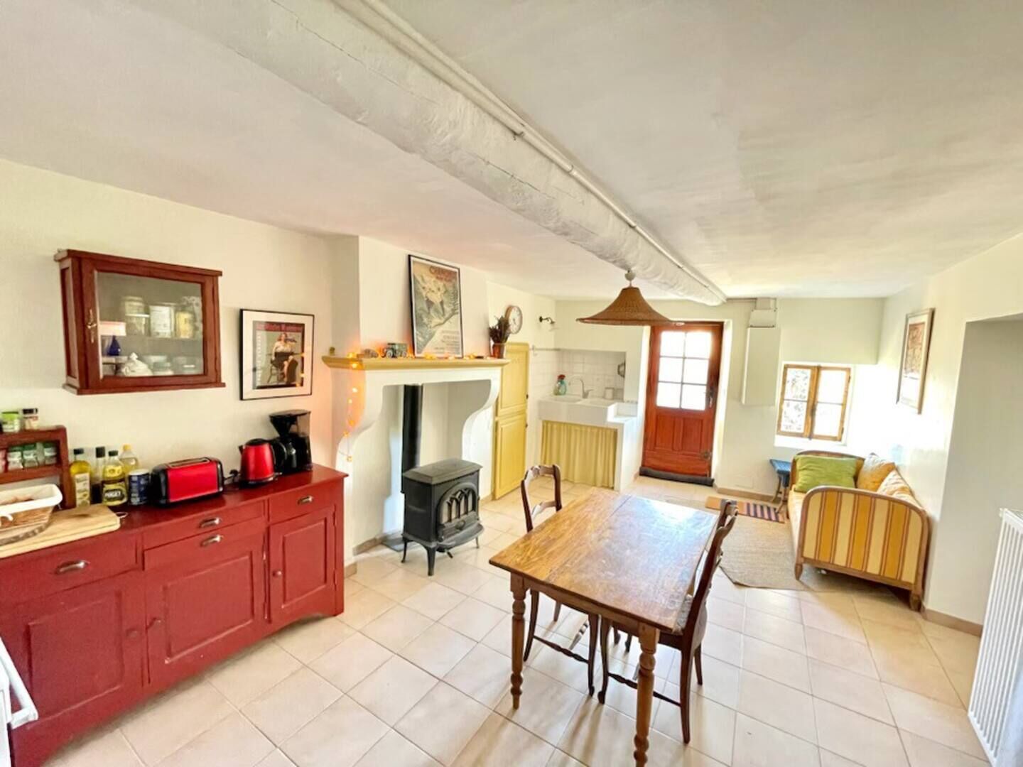 Une cuisine spacieuse avec une table à manger, des placards rouges et un poêle à bois.