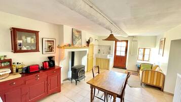 Une cuisine spacieuse avec une table à manger, des placards rouges et un poêle à bois.