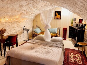 A bedroom with a canopy bed, a desk with a chair, a red cabinet, and a poster on the wall.