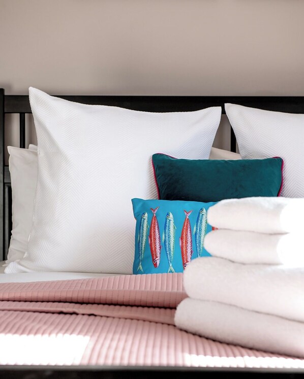 A neatly made bed with white and teal pillows, a pink blanket, and a black headboard. - The Royal Oak Hotel (Hawkhurst)