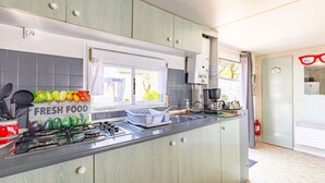 A kitchen with a window, a dish rack, and a sign that says 'FRESH FOOD'.