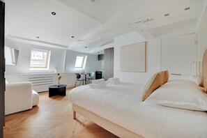 A modern bedroom with a large bed, a desk, and a chair.