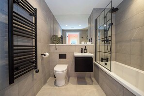 Ein modernes Badezimmer mit Toilette, Waschbecken und einer Duschkabine.