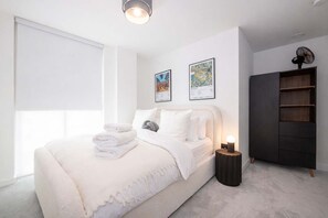 Ein modernes Schlafzimmer mit Bett, Nachttisch, Kunstwerk und Kleiderschrank.