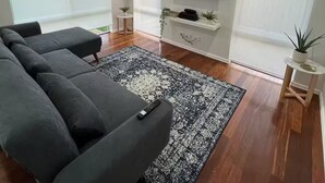 En moderne stue med en hjørnesofa, et fladskærms-tv og et lille sofabord med en plante.