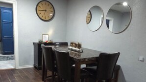 Un comedor con una mesa y sillas de madera, un reloj y dos espejos en la pared.