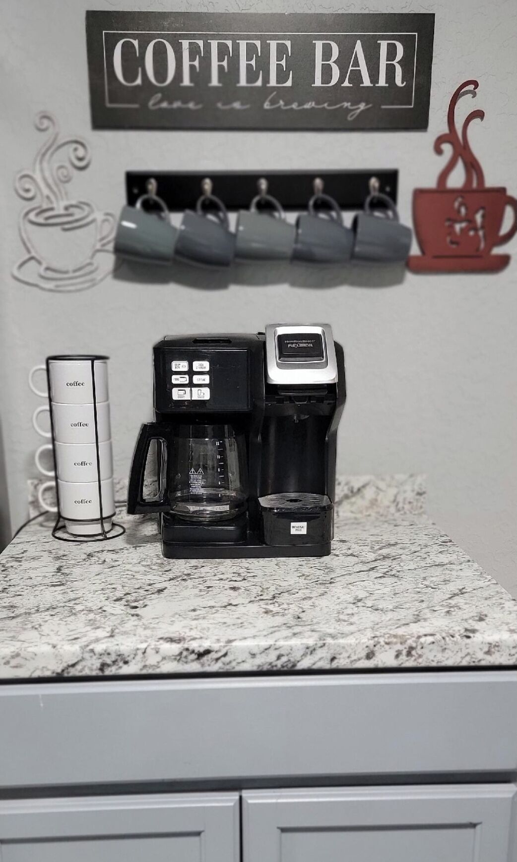 Une machine à café est posée sur un plan de travail de cuisine, avec une tasse à café à côté.