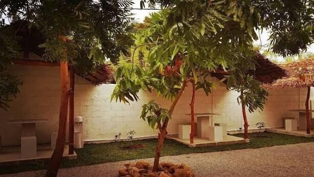 A courtyard with a white brick wall, a small garden area, and a seating area with benches. - BEDBOX (Dambulla,)