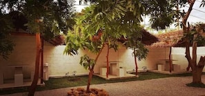 Une cour avec un mur en briques blanches, un petit jardin et un espace aménagé avec des bancs.