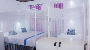 A room with two beds, each covered with a white canopy. There is a white cabinet with red handles in the center of the room. - BEDBOX (Dambulla,)