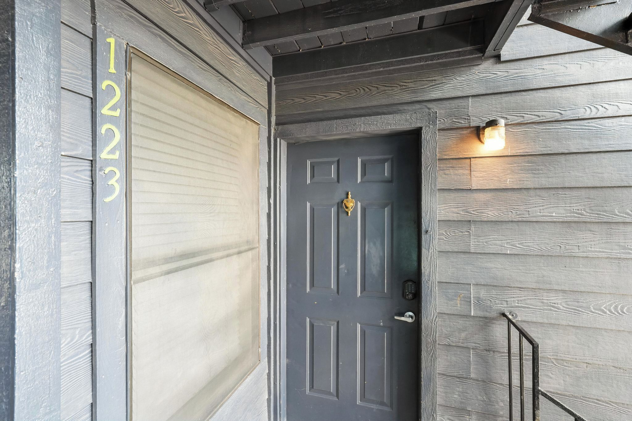 A dark wooden door with a keypad lock and a small light fixture above it.