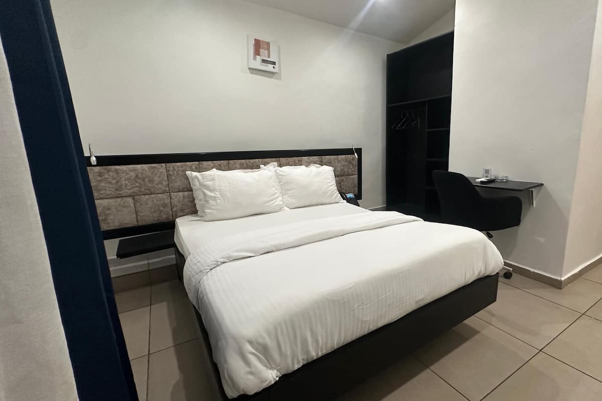 Una camera da letto ordinata con un letto, un comodino e una scrivania con una sedia.