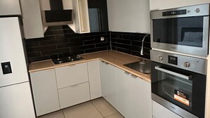 Eine moderne Küche mit weißen Schränken, einer schwarzen Spritzschutzwand und einem Doppelbackofen.