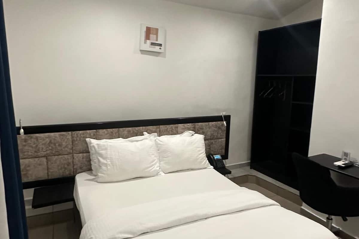 Una moderna camera d'albergo con un letto grande, un comodino, una scrivania e un armadio.