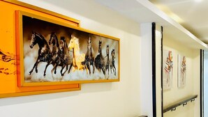 Ein Flur mit einem gerahmten Kunstwerk von Pferden, einer Handläufe und einem gefliesten Boden.