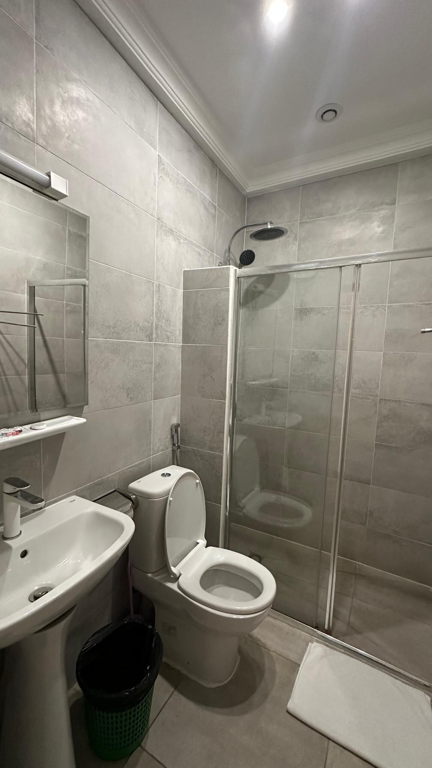 Un baño moderno con inodoro, lavabo y ducha con mampara de vidrio.
