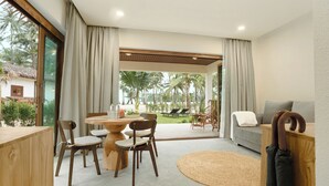 Una sala moderna con comedor, sofá y vista a palmeras.