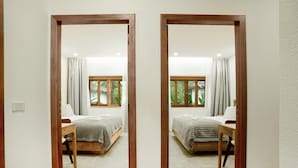 Reflejo de un dormitorio con dos camas, cabeceros de madera y una ventana con cortinas.