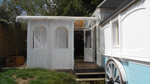 A small white wooden structure with arched windows and a wooden staircase leading to a door. - Chambre d'hôte .Lodge Jardin Secret - cosy accommodation with breakfast (Arlanc)