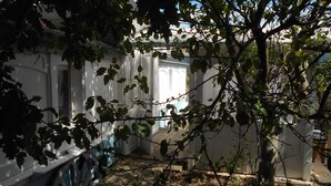 A white building with a blue door, surrounded by trees and a wooden deck. - Chambre d'hôte .Lodge Jardin Secret - cosy accommodation with breakfast (Arlanc)