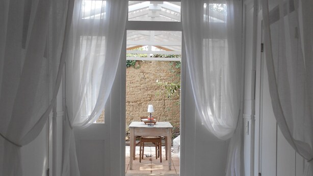 A room with a wooden floor, white curtains, and a table with chairs outside. - Chambre d'hôte .Lodge Jardin Secret - cosy accommodation with breakfast (Arlanc)